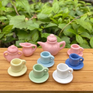 May include: A miniature tea set with a pink teapot, creamer, sugar bowl, and six pastel-colored teacups and saucers.