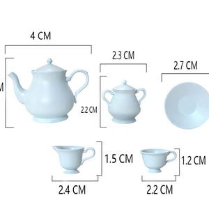 May include: A light blue tea set with a teapot, creamer, sugar bowl, cup, and saucer. The set is 4 cm tall, 2.7 cm wide, and 2.2 cm deep.