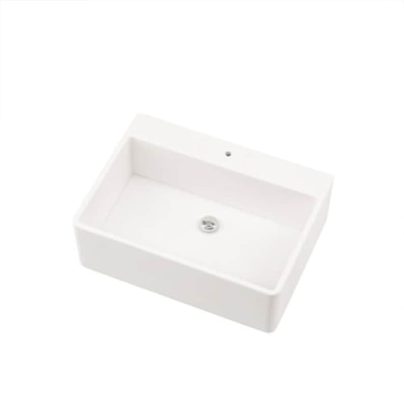 May include: A rectangular, white ceramic bathroom sink with a single faucet hole and a chrome drain. The sink has a modern, minimalist design, perfect for a contemporary bathroom. The sink is clean and bright.
