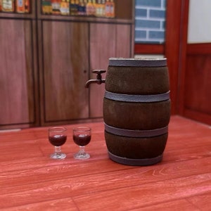 Pode incluir: Um barril de madeira com uma torneira de metal, duas pequenas ta&ccedil;as de vinho cheias de vinho tinto e um ch&atilde;o de madeira.