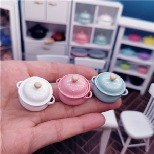 May include: Three miniature enamel pots with lids. The pots are white, pink, and light blue. The lids have wooden knobs.