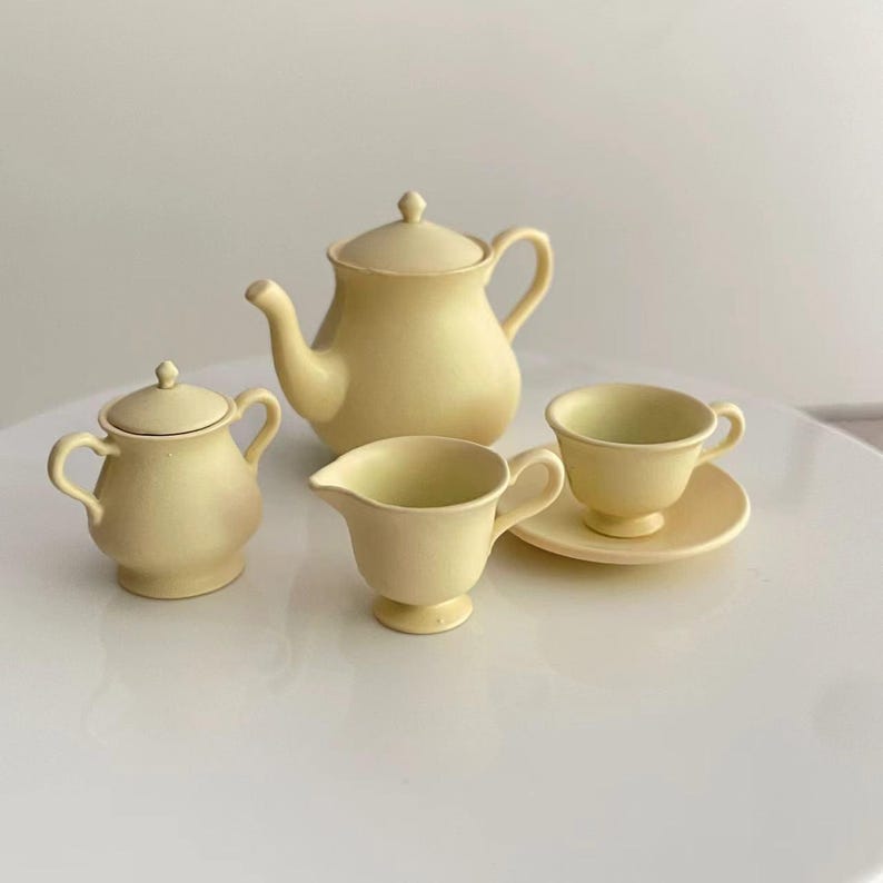 May include: A yellow tea set with a teapot, creamer, sugar bowl, and a cup and saucer.