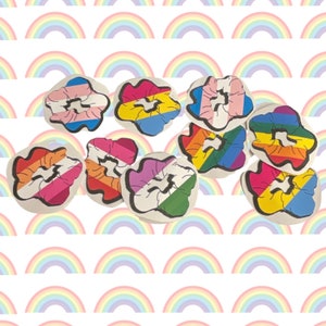 May include: Nine colorful hair scrunchies with rainbow stripes and patterns. The scrunchies are arranged in a circle on a white background with a rainbow pattern.