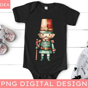 May include: A black baby onesie with a watercolor illustration of a toy soldier. The soldier is wearing a red and white hat, a green uniform, and holding a candy cane.