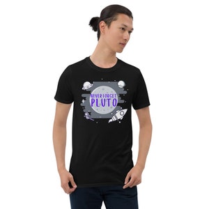 May include: Black t-shirt with a graphic of a moon, stars, a rocket, and a UFO. The text "NEVER FORGET PLUTO" is written in purple on the moon.