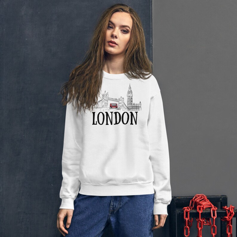 May include: White sweatshirt with a black and white illustration of the London skyline, including Big Ben and a red double-decker bus. The text "LONDON" is printed in black below the illustration.