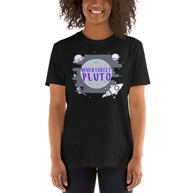 May include: Black t-shirt with a graphic of a moon, stars, a rocket, a spaceship, and an astronaut. The text "NEVER FORGET PLUTO" is written in purple on the moon.