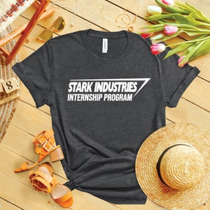 May include: A dark heather grey t-shirt with a white graphic that reads "Stark Industries Internship Program".