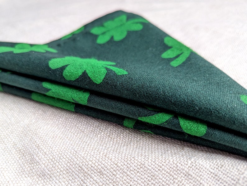 Puede incluir: Una tela verde doblada con un patr&oacute;n de tr&eacute;bol. La tela es verde oscuro con tr&eacute;boles verde claro.