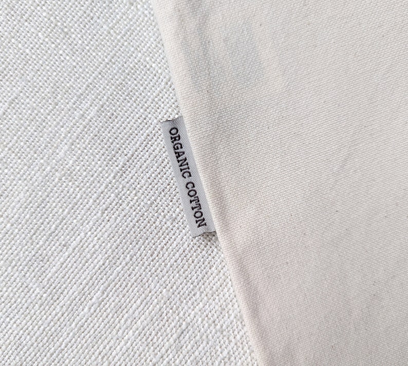 Peut inclure: Un gros plan sur une &eacute;tiquette en tissu blanc avec le texte "ORGANIC COTTON" imprim&eacute; en noir.
