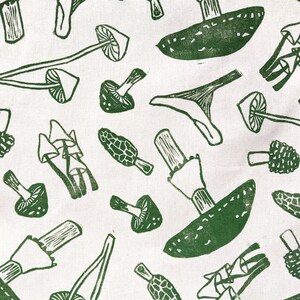 May include: A white fabric with a green repeating pattern of various mushrooms. The mushrooms are drawn in a simple, stylized way.