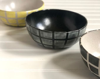 May include: Three ceramic bowls with a checkered pattern. The bowls are black, white, and yellow.