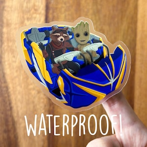 May include: A waterproof sticker featuring Rocket Raccoon and Groot in a blue and yellow vehicle. The sticker has the word "WATERPROOF!" printed in white.