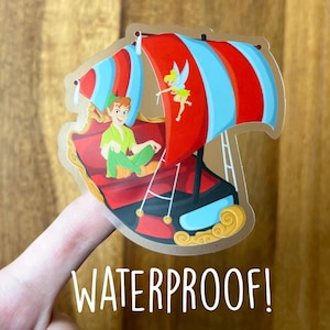 May include: A clear sticker featuring Peter Pan and Tinkerbell on a pirate ship with red and blue sails. The sticker has the word "WATERPROOF!" in white text.