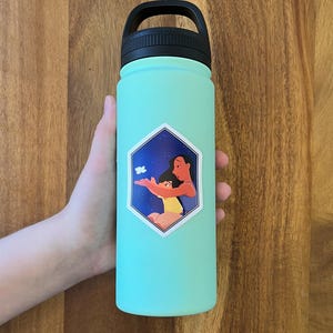 K&ouml;nnte beinhalten: Eine t&uuml;rkisfarbene Wasserflasche mit schwarzem Deckel und Griff. Auf der Flasche befindet sich ein Aufkleber mit einer Frau und einem Kind mit einem Schmetterling.