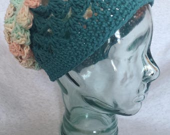 May include: A teal crochet beanie with a multi-colored crocheted flower design on the side.