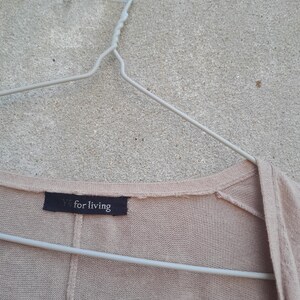 K&ouml;nnte beinhalten: Hellbeige Cardigan an einem wei&szlig;en Metallb&uuml;gel. Das Etikett zeigt "Y's for living" in wei&szlig;er Schrift auf schwarzem Hintergrund. Der Cardigan ist aus weichem Strickmaterial gefertigt.