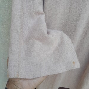 K&ouml;nnte beinhalten: Ein lang&auml;rmeliges Hemd mit zweifarbigem Design. Der obere Teil des Hemdes ist hellbeige, w&auml;hrend der untere Teil braun ist. Der &Auml;rmel ist sichtbar und zeigt die Textur des Stoffes.