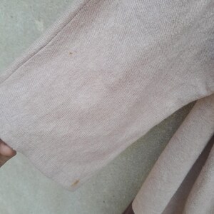 K&ouml;nnte beinhalten: Nahaufnahme eines beige-braunen Pullover&auml;rmels. Der &Auml;rmel ist einfarbig beige mit einem braunen Streifen am unteren Rand. Der Stoff scheint ein weiches Strickmaterial zu sein.