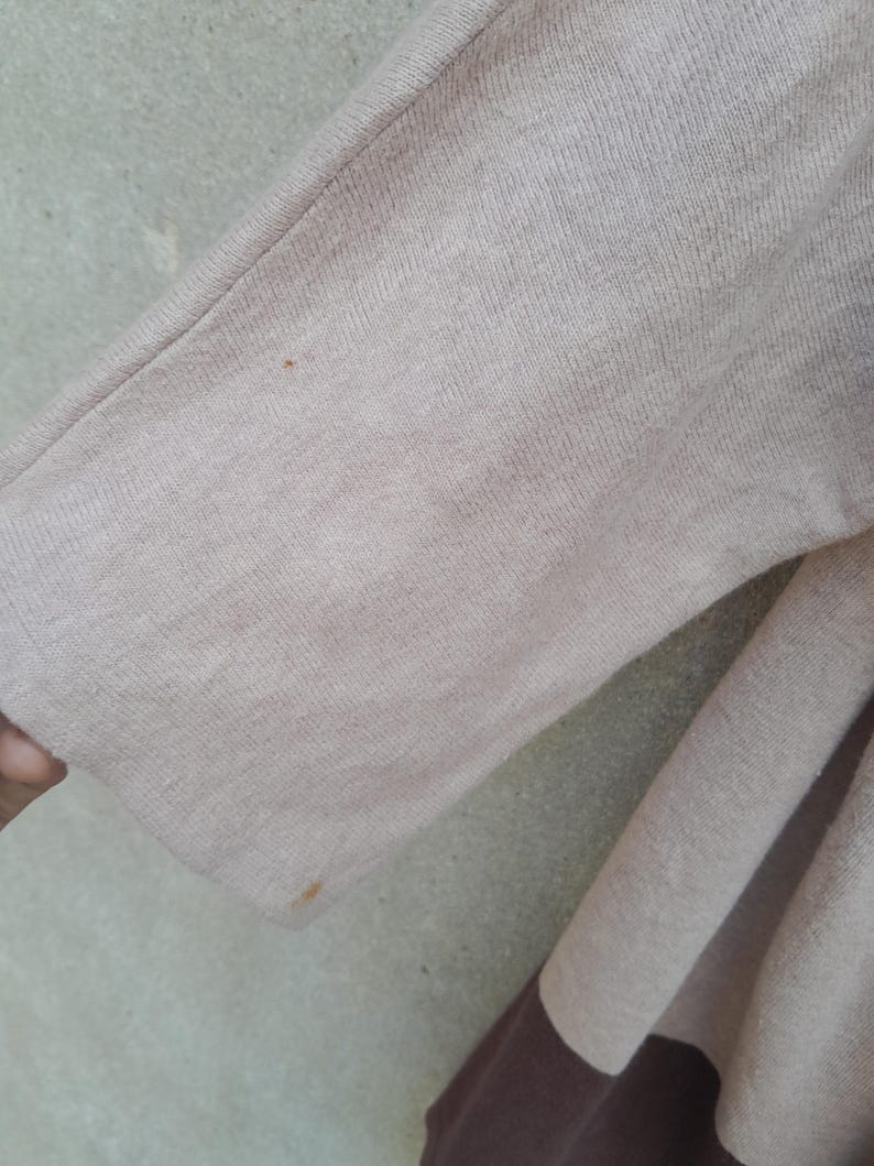 K&ouml;nnte beinhalten: Nahaufnahme eines beige-braunen Pullover&auml;rmels. Der &Auml;rmel ist einfarbig beige mit einem braunen Streifen am unteren Rand. Der Stoff scheint ein weiches Strickmaterial zu sein.