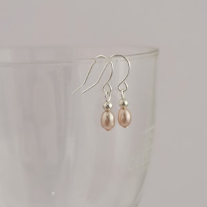 Peut inclure: Une paire de boucles d'oreilles pendantes en argent avec une perle rose clair sur chaque boucle d'oreille.