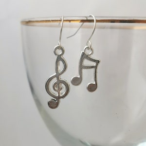May include: Silver musical note earrings. One earring features a treble clef and the other a quarter note.