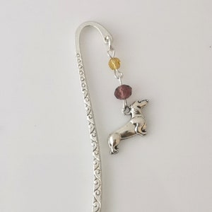 May include: Silver bookmark with a dachshund charm and purple and yellow beads.