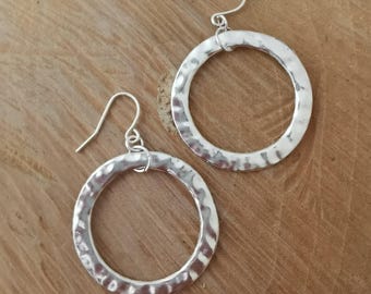 May include: A pair of silver hoop earrings with a hammered texture. The earrings are simple and elegant.
