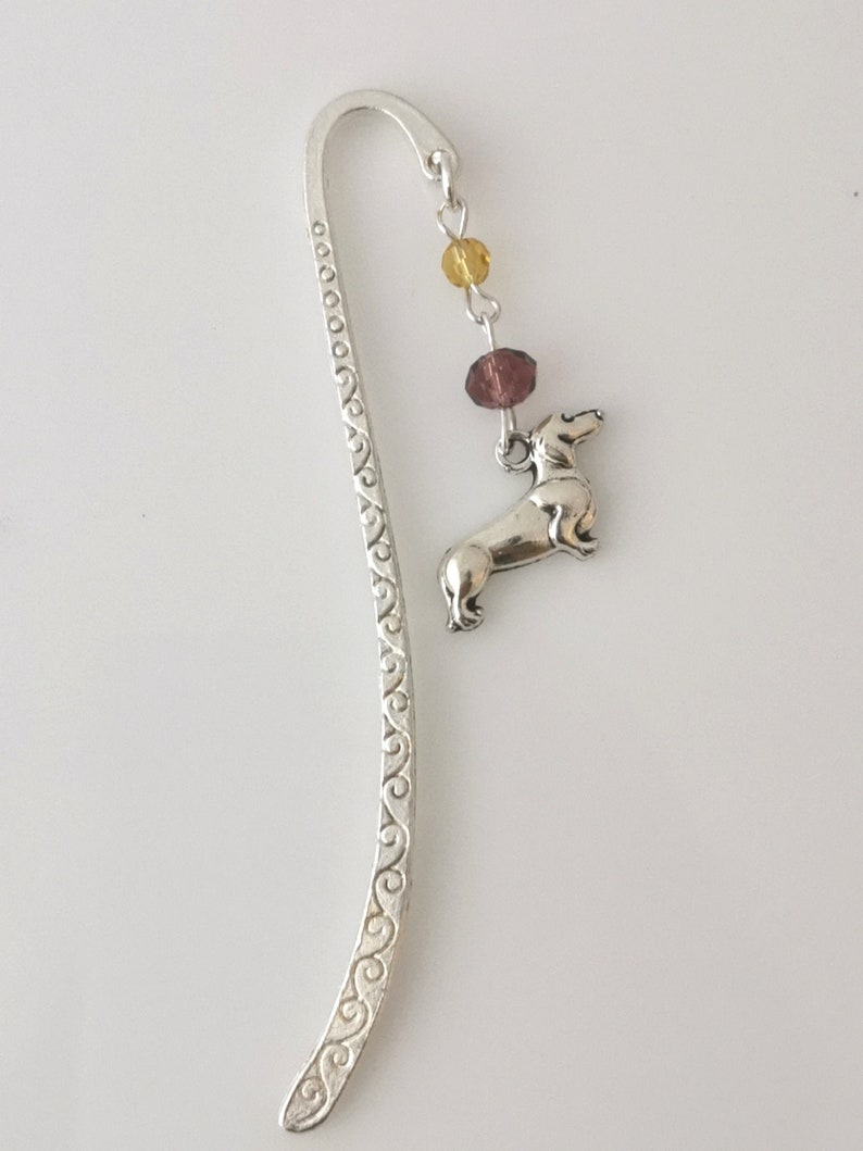 May include: Silver bookmark with a dachshund charm and purple and yellow beads.