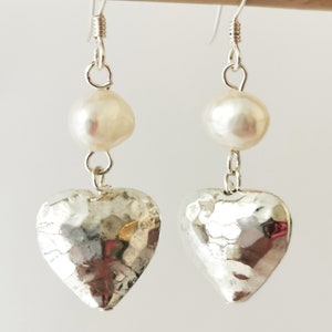 May include: Silver heart earrings with a white pearl on each earring.