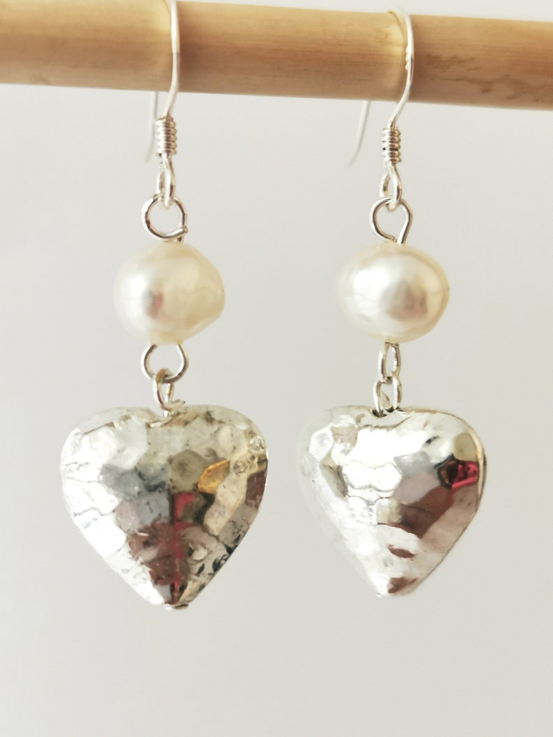 May include: Silver heart earrings with a white pearl on each earring.