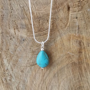 May include: A silver chain necklace with a turquoise teardrop pendant.