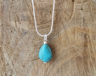 Puede incluir: Un collar de cadena de plata con un colgante de lágrima turquesa.