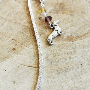 May include: Silver bookmark with a dachshund charm and a chain with purple and yellow beads.