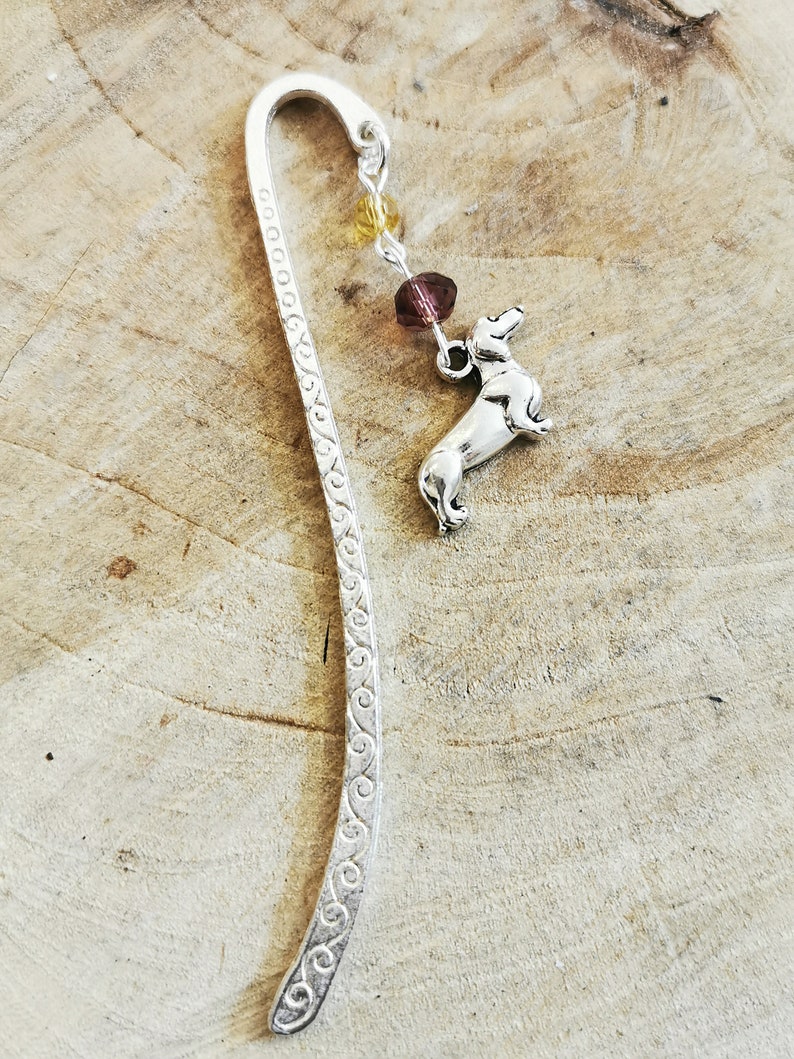 May include: Silver bookmark with a dachshund charm and a chain with purple and yellow beads.