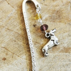 May include: Silver bookmark with a dachshund charm and a chain of brown and yellow beads.