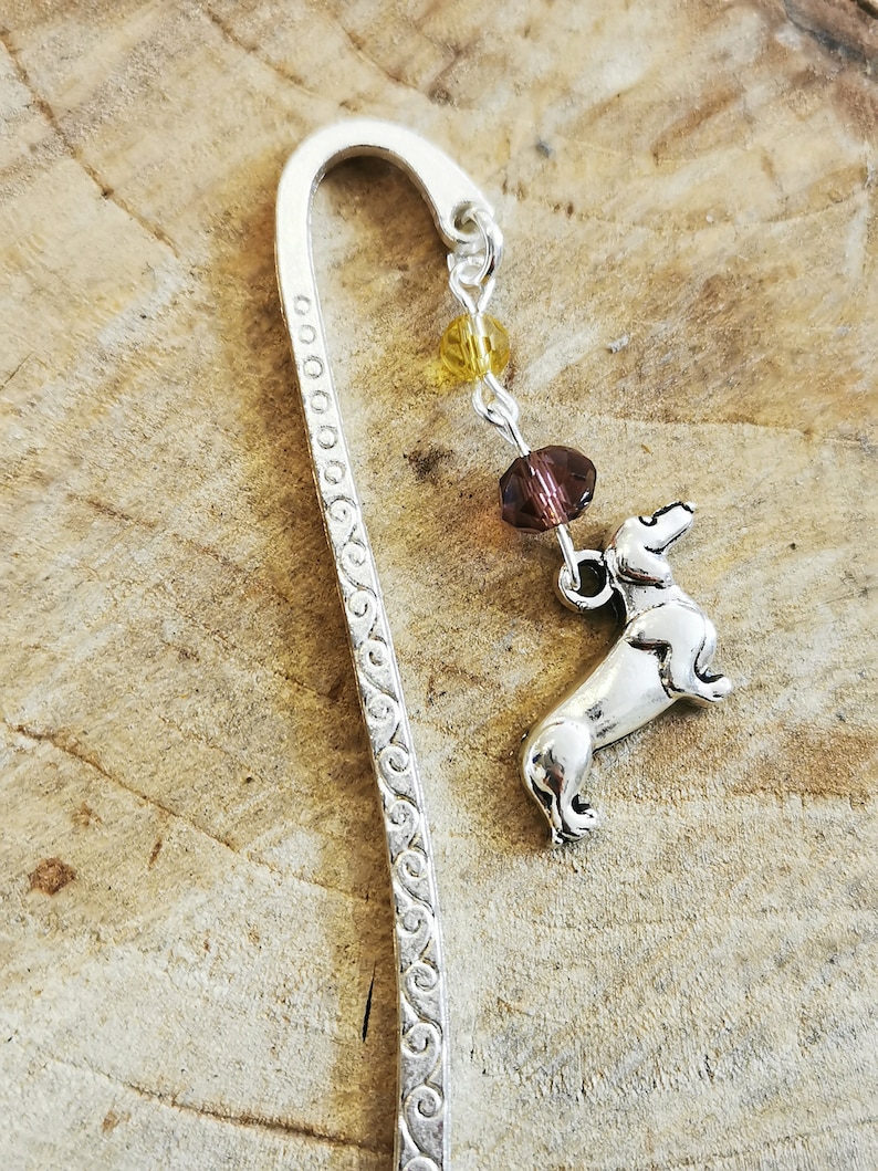 May include: Silver bookmark with a dachshund charm and a chain of brown and yellow beads.