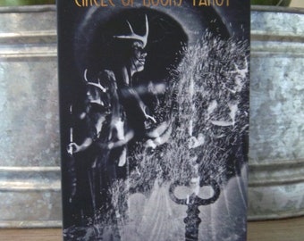 May include: A tarot card deck titled "Circle of Doors Tarot" with a black and white illustration. The image features a mystical figure with antlers, a key, and a swirling, ethereal background. The text is in gold.