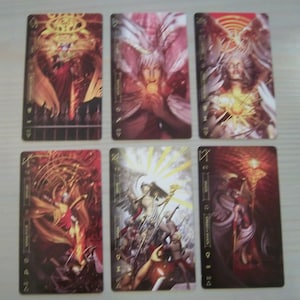May include: Six tarot cards with gold trim and black backgrounds. The cards feature illustrations of angels and figures in various poses. The card titles are "The World", "The Sun", "The Star", "The Moon", "The Tower", and "The Devil".
