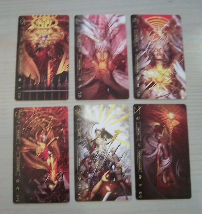 May include: Six tarot cards with gold trim and black backgrounds. The cards feature illustrations of angels and figures in various poses. The card titles are "The World", "The Sun", "The Star", "The Moon", "The Tower", and "The Devil".