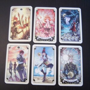 May include: Six tarot cards with illustrations of people and symbols. The cards are in a white frame with gold accents. The cards are numbered 1 through 6. The cards are from a tarot deck called "The Enchanted Tarot".