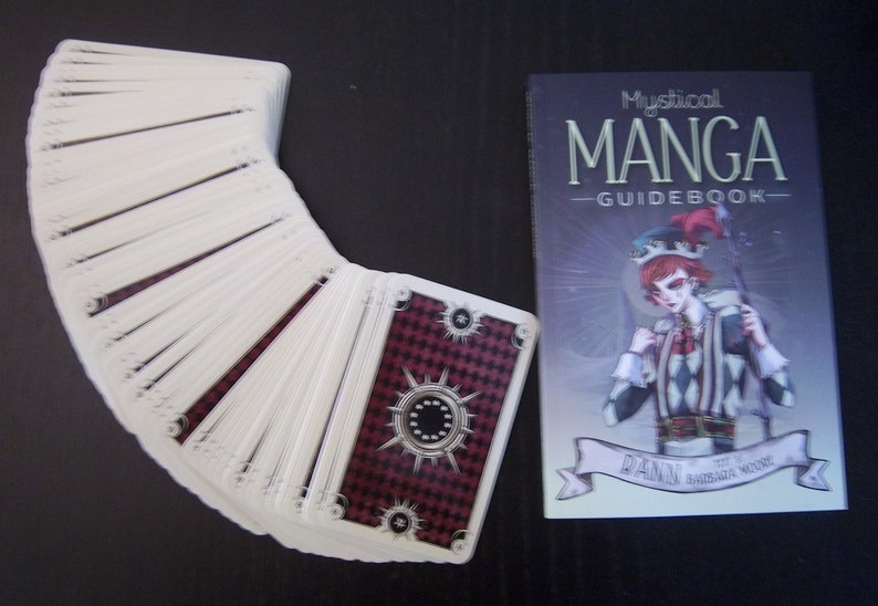 May include: A deck of Mystical Manga Guidebook tarot cards with a red and black checkered design on the back of the cards. The guidebook features a jester character with a red and white checkered costume.