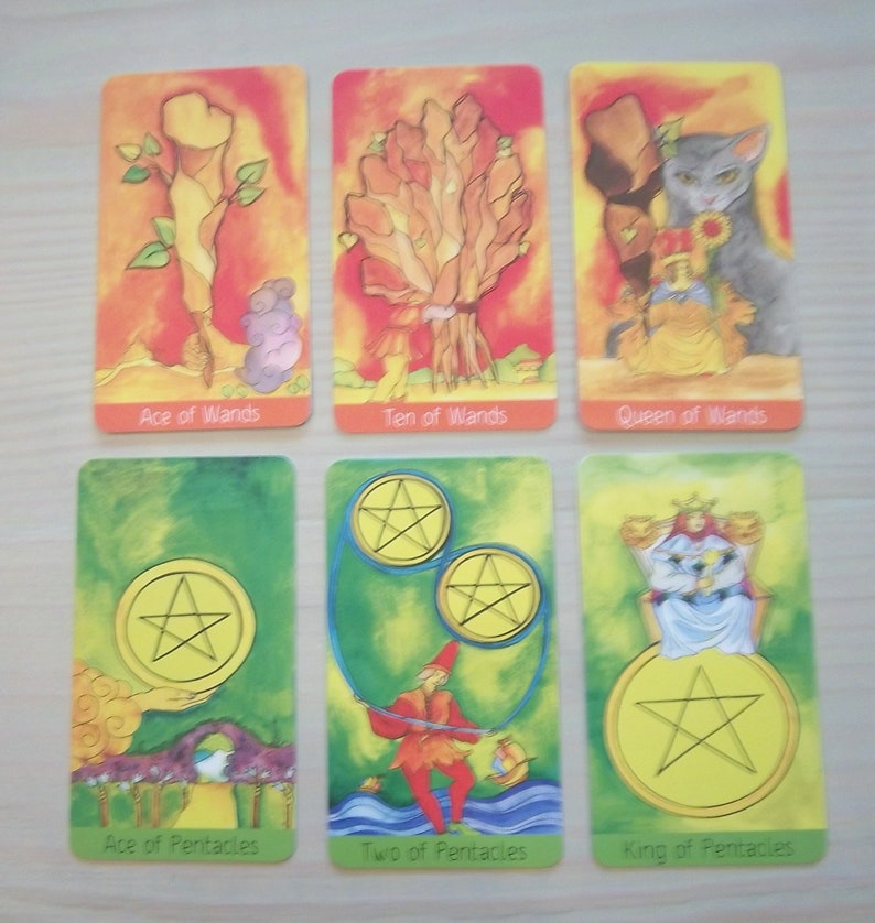 May include: Tarot card deck featuring colorful illustrations of the Ace of Wands, Ten of Wands, Queen of Wands, Ace of Pentacles, Two of Pentacles, and King of Pentacles.