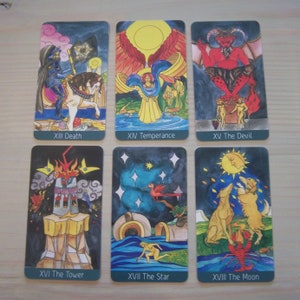 May include: A set of tarot cards with colorful illustrations depicting various scenes from the Major Arcana. The cards are arranged in two rows of three, with the card titles visible at the bottom of each card. The cards include Death, Temperance, The Devil, The Tower, The Star, and The Moon.