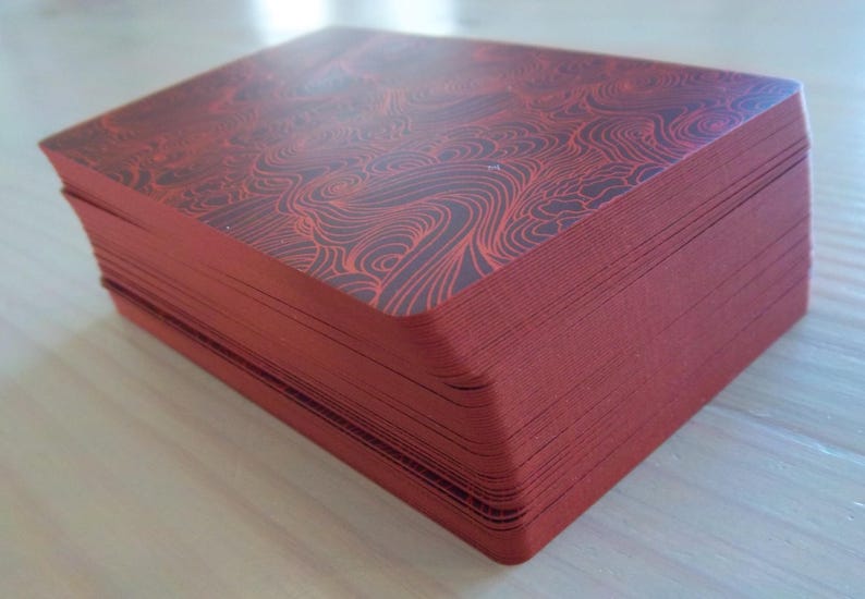 May include: A stack of red playing cards with a black and red patterned design on the top card.