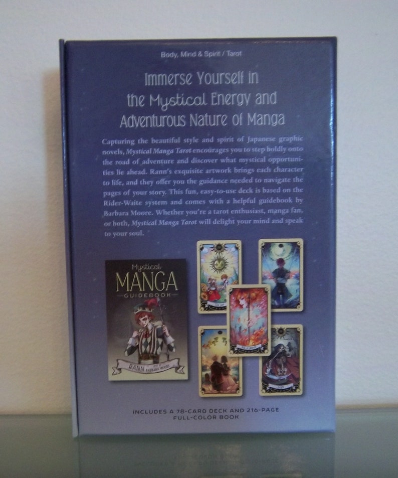 May include: A purple box with a tarot deck titled "Mystical Manga Guidebook" featuring a 78-card deck and a 216-page full-color book. The box shows images of the cards with colorful illustrations of characters and scenes.