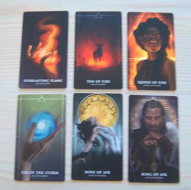 May include: Tarot cards featuring illustrations of fire, air, and water elements. The cards depict a hand holding a flame, a deer in a forest, a woman with long dark hair, a hand holding a blue orb, a woman in a white dress, and a man with a beard holding a sword.