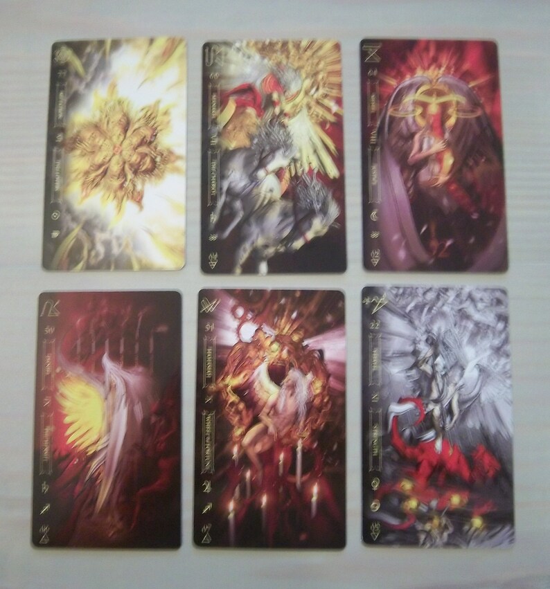 May include: Six tarot cards with gold trim and black backgrounds. The cards feature illustrations of angels and other figures in various poses. The cards are numbered 1-6 and have the names of the corresponding tarot cards written on them.