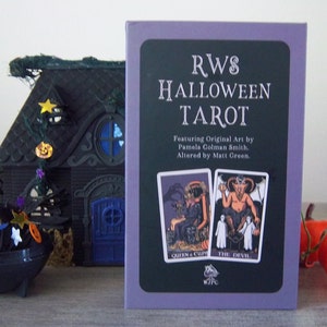 May include: A purple box with the text "RWS HALLOWEEN TAROT" on the front. The box features two tarot cards, the Queen of Cups and The Devil, with original art by Pamela Colman Smith, altered by Matt Green.