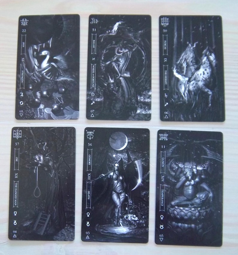 May include: Six tarot cards with dark, gothic illustrations. The cards feature images of Strength, Wheel of Fortune, The Hermit, The Hanged Man, Death, and Temperance. Each card has a unique design with black and white artwork.